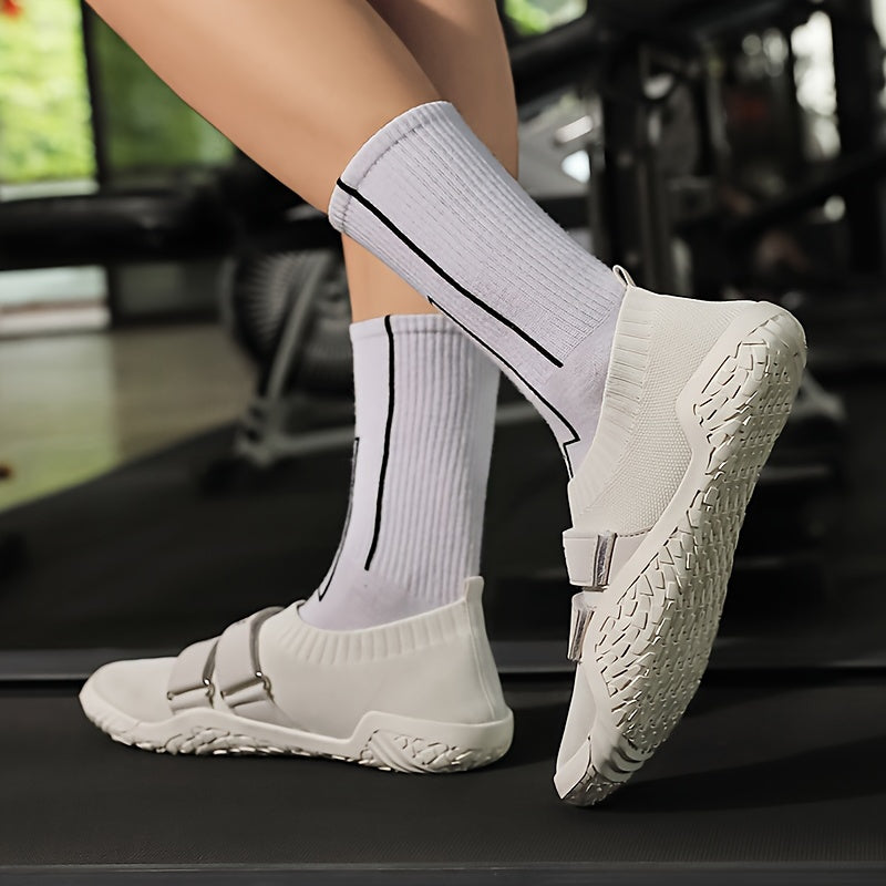 White shoes for lifting weights with black accents worn by a person on a blurred indoor background