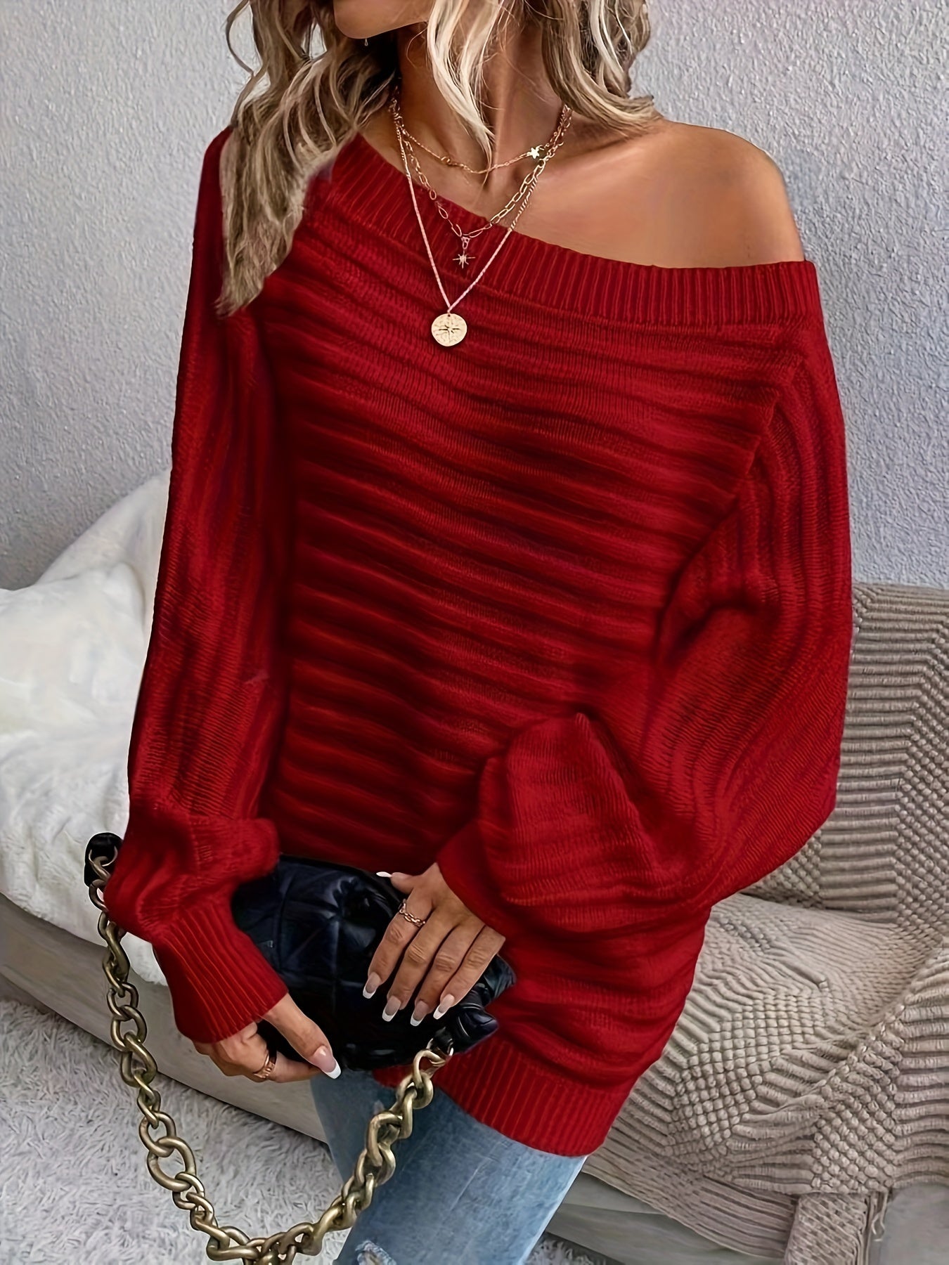 Person wearing a red off shoulder sweater with a neutral background