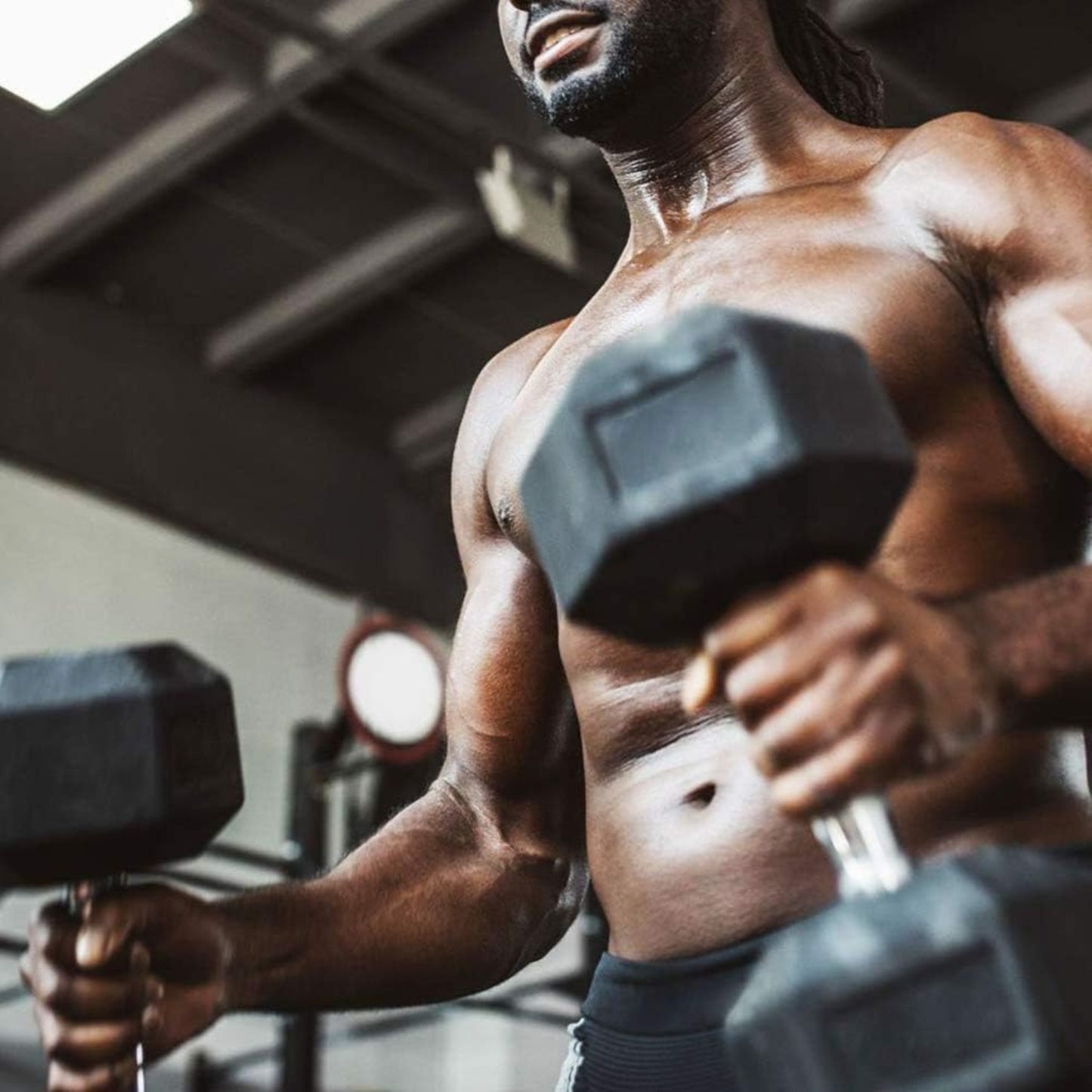Muscular man lifting hex dumbbells in a gym setting
