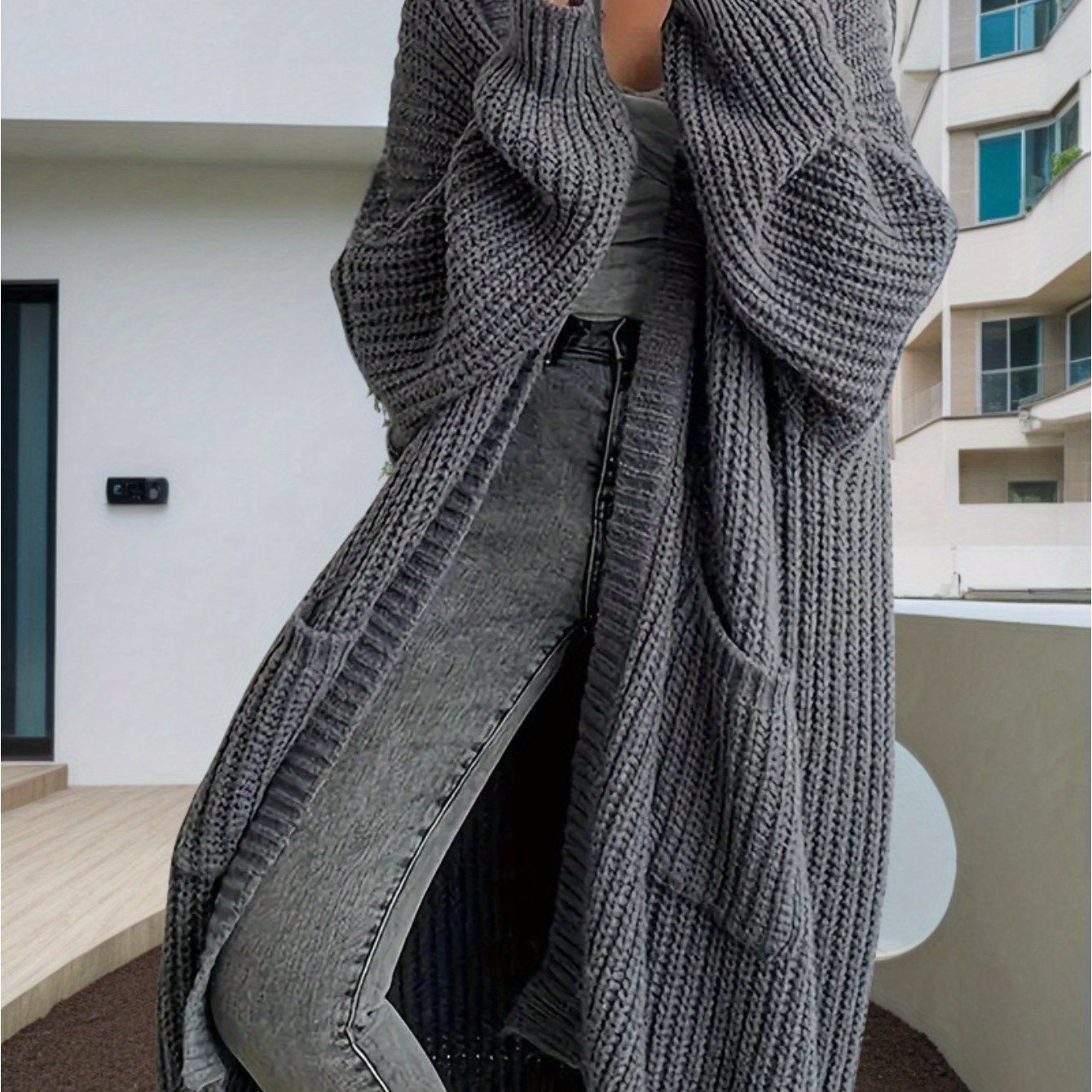 Person wearing a long gray knitted cardigan in an urban setting