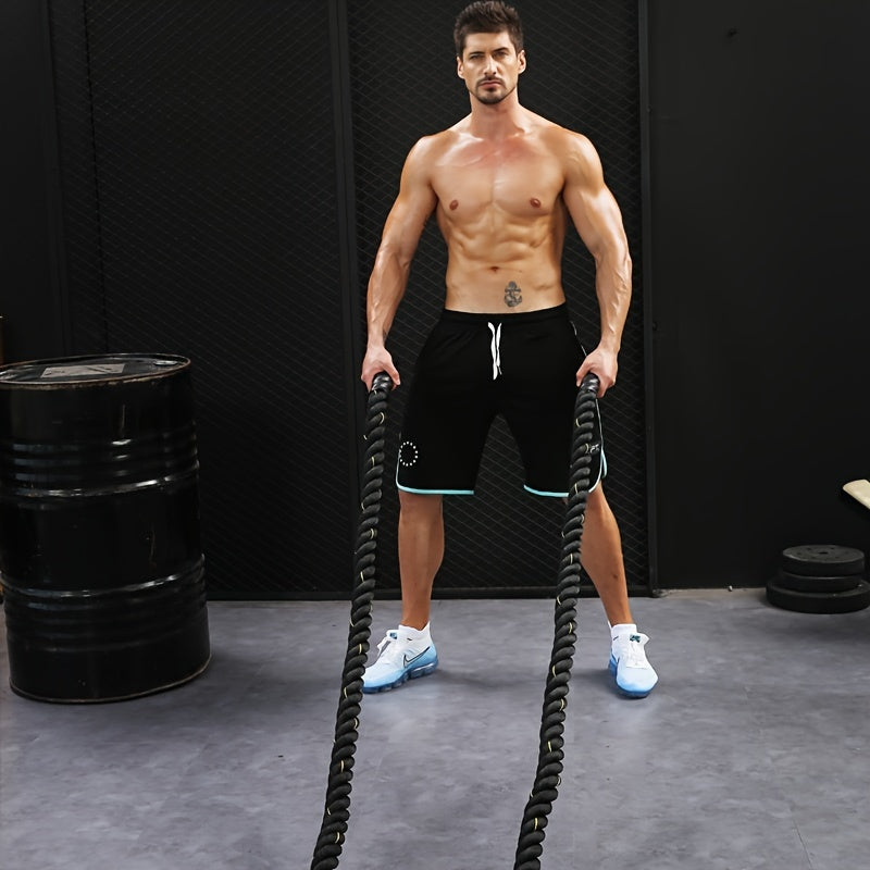 Muscular man holding exercise battle ropes in a gym setting