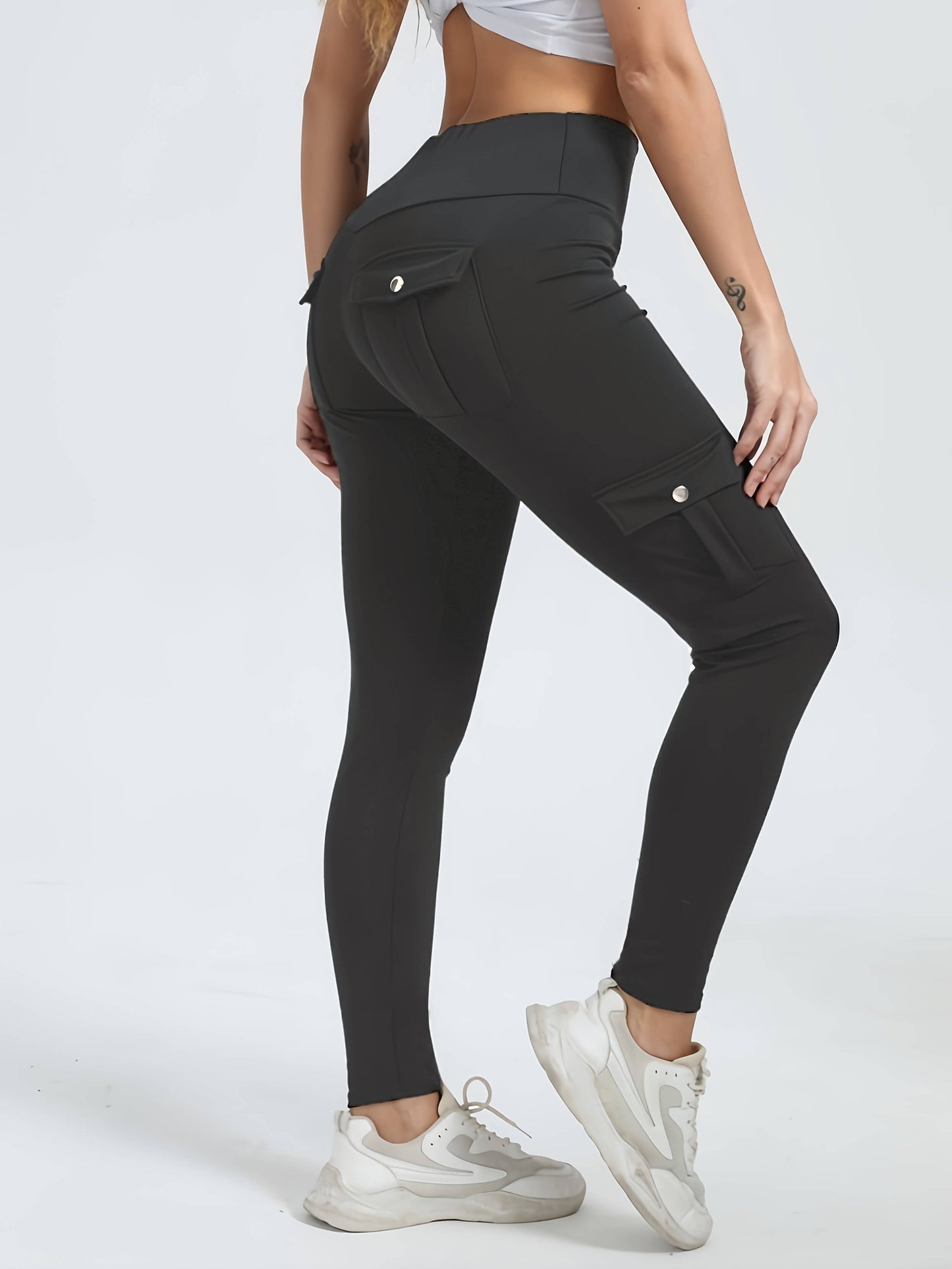 The side view of a woman wearing a pair of grey yoga legging sold by 100 Spartans