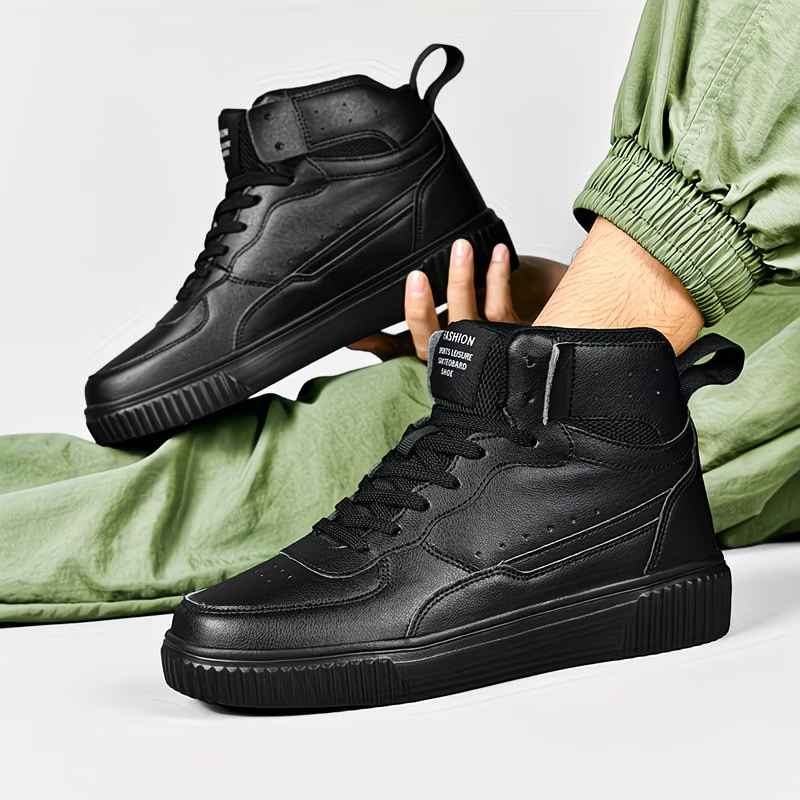 Black high-top sneakers with a person wearing green pants on a light gray background