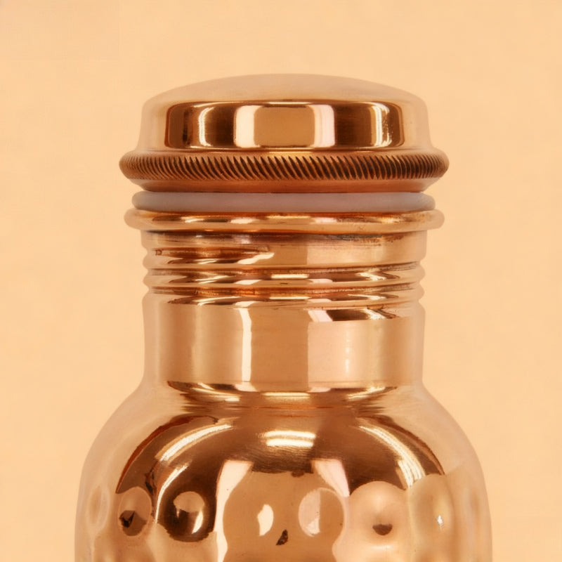Rose gold bottle with a textured cap on a beige background