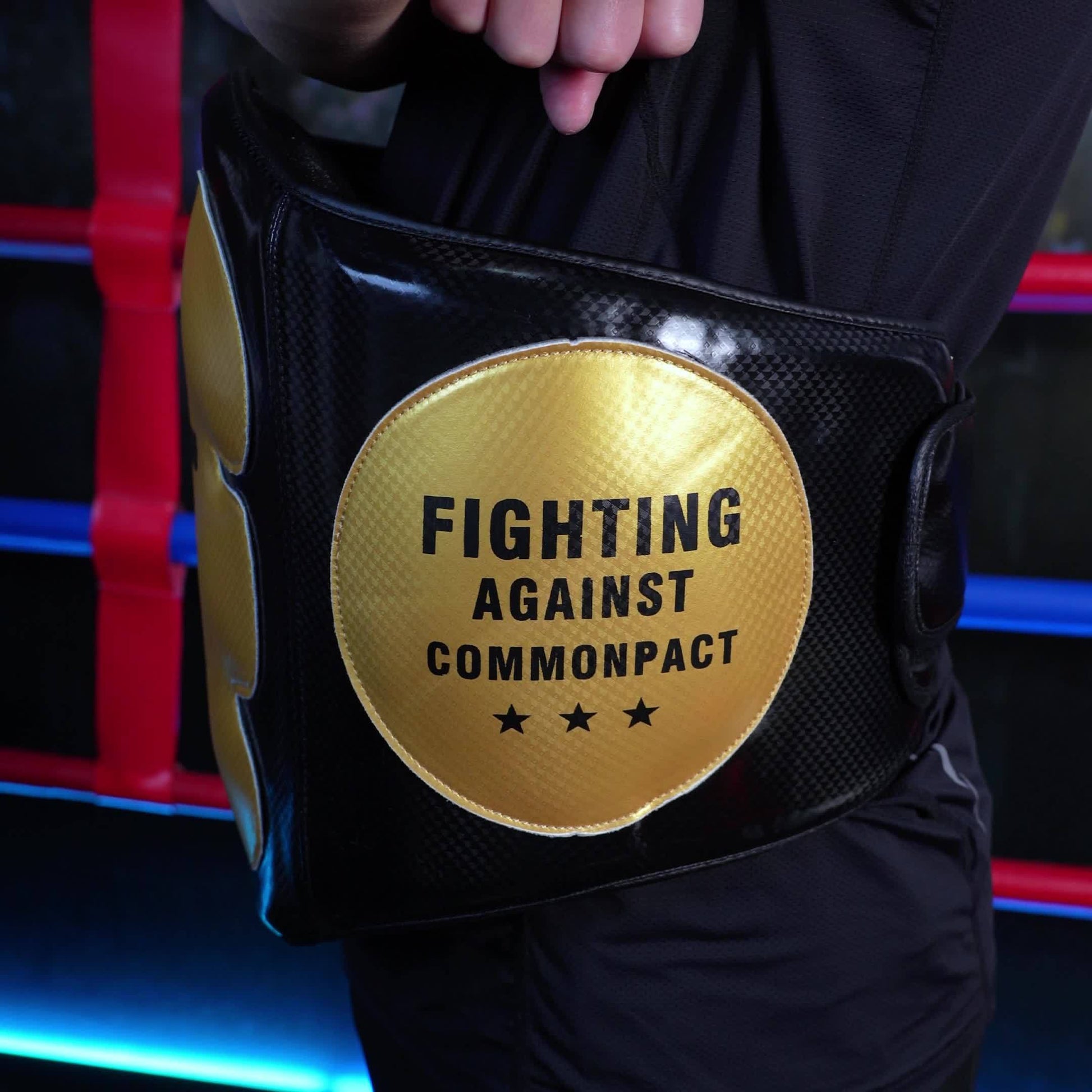 Black championship belt with gold patch in a boxing ring