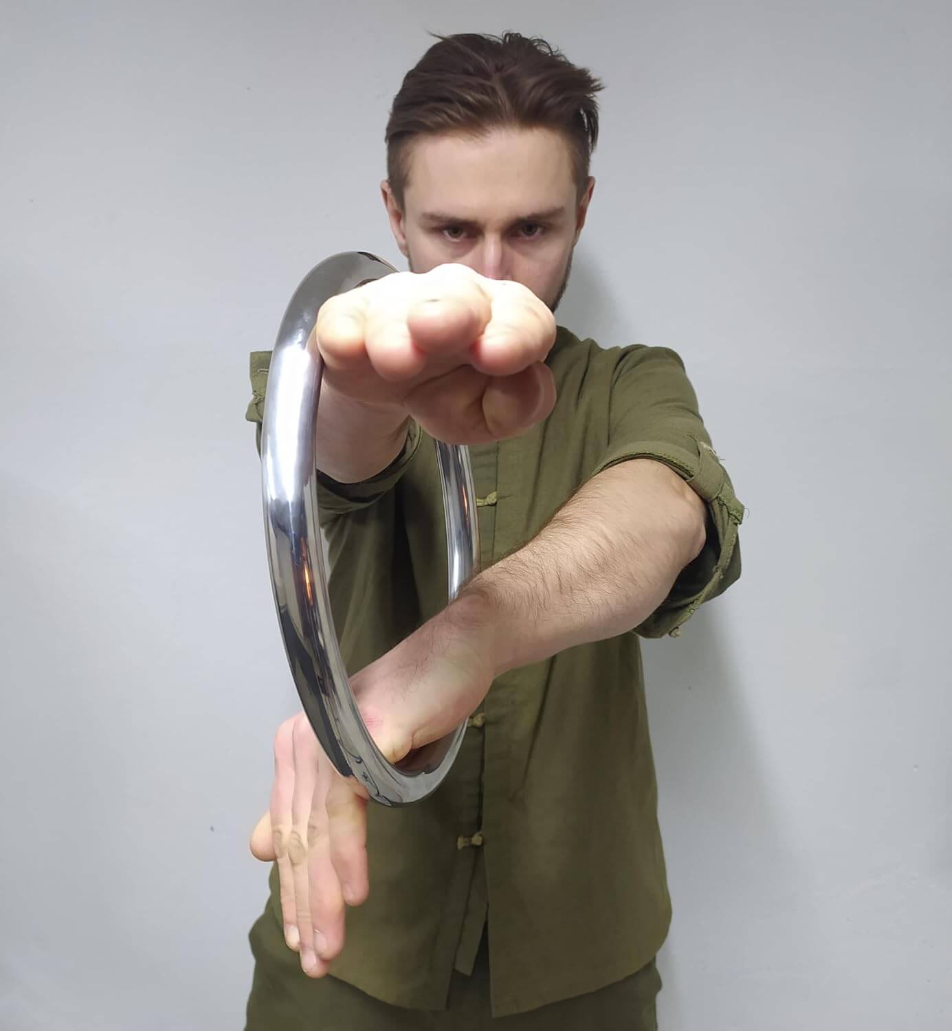 A man training with a wing chun ring against a plain background