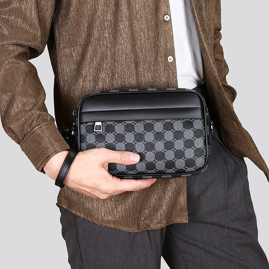 Person holding a black and gray checkered leather toiletry bag against a neutral background