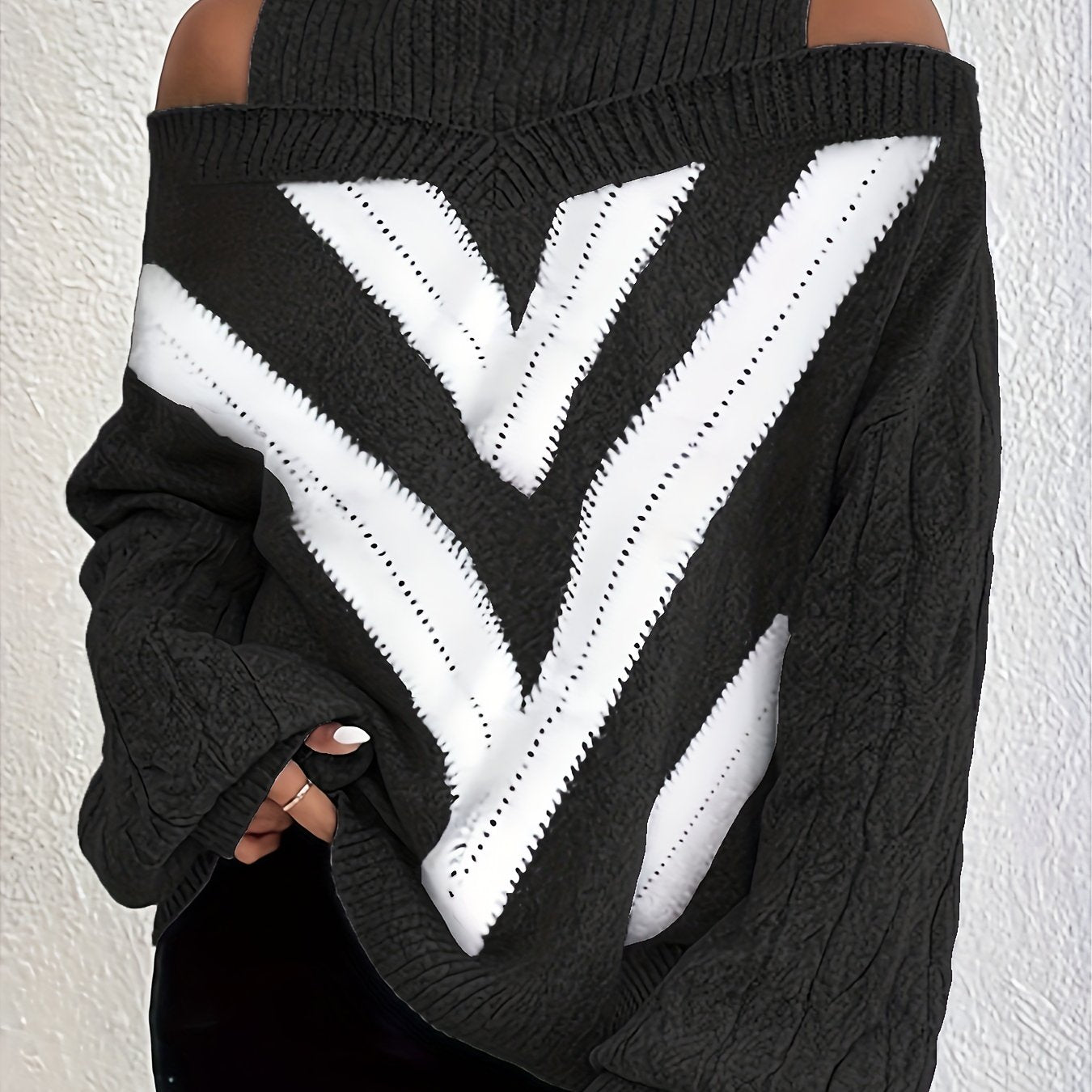 Black off the shoulder sweater with white V-shaped pattern on a plain background
