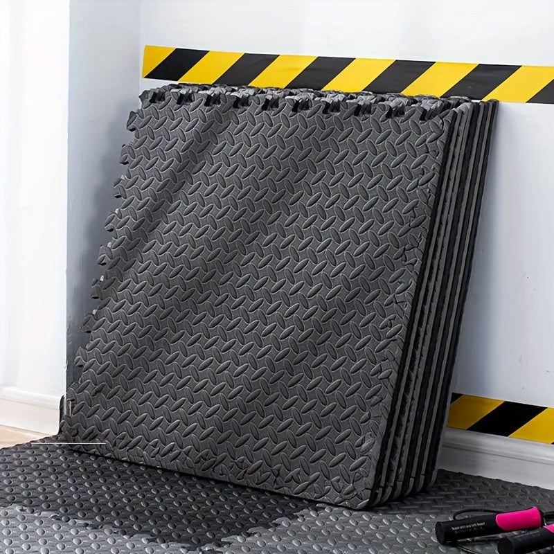 Stack of gray foam mats with a black and yellow striped warning tape on top, against a white wall.