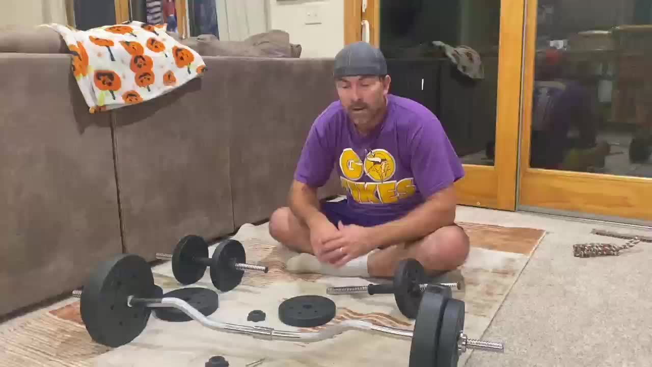 Man sitting on the floor with weightlifting equipment in a home setting