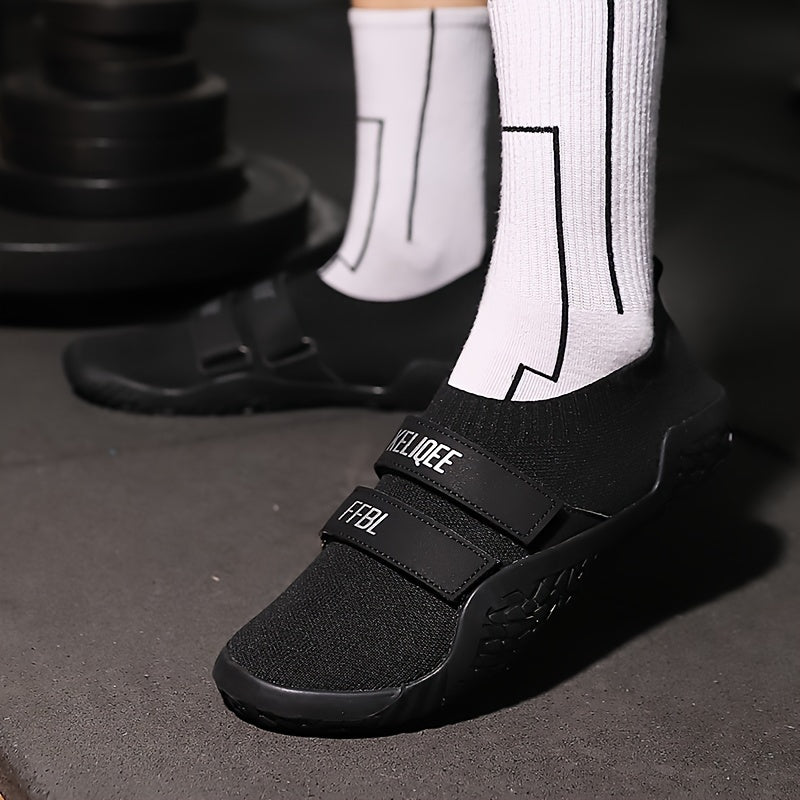 Black shoes for lifting weights with velcro straps worn with white socks on a dark surface