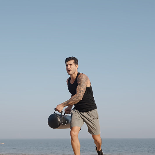 Man holding a water weight bag​ on a beach with a clear sky