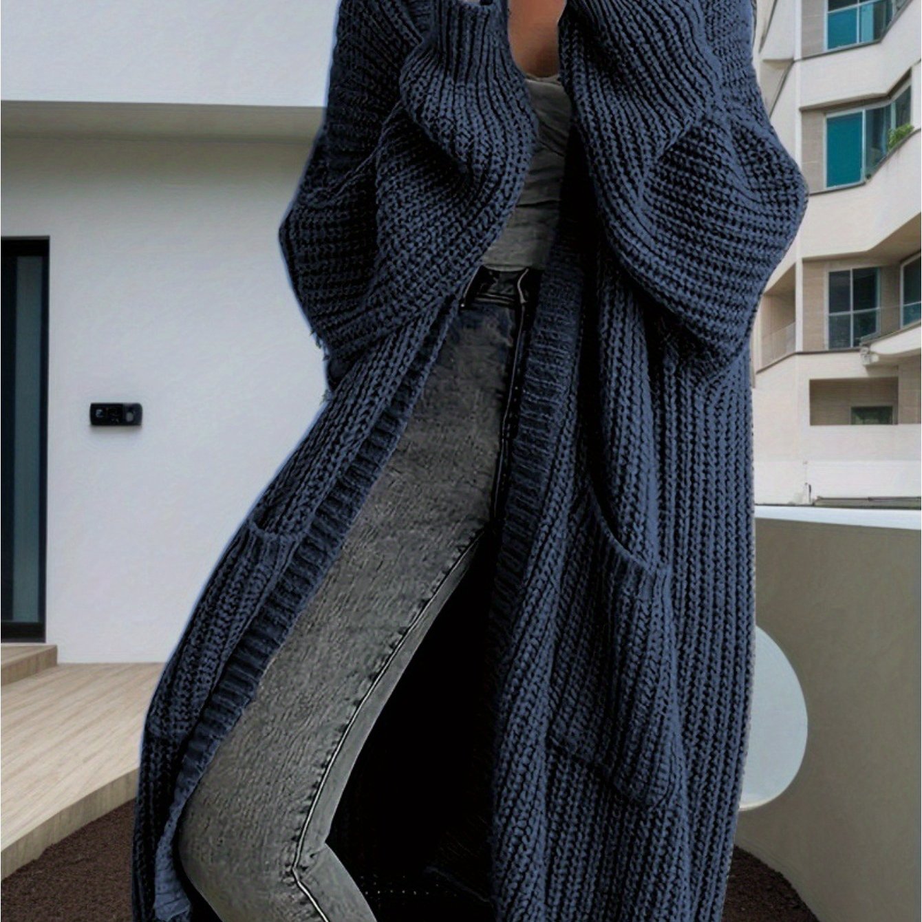 Person wearing a long dark blue knitted cardigan in an urban setting