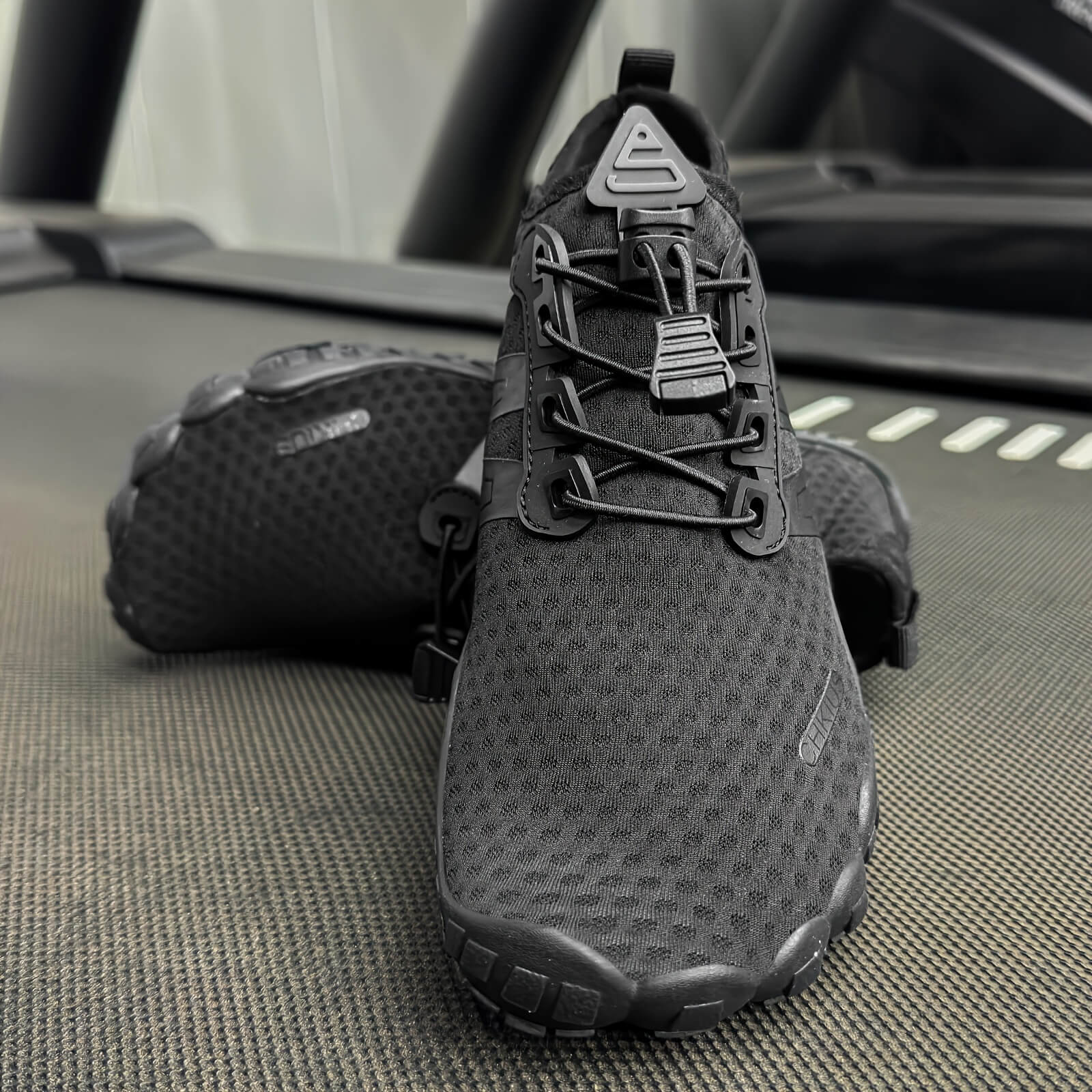 Black deadlift shoes on a textured surface with a blurred background