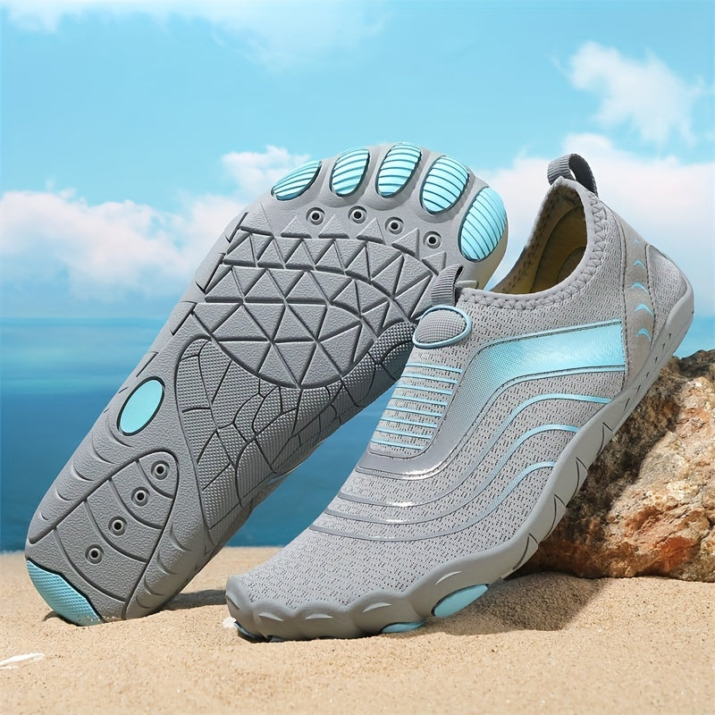 Gray and light blue water hiking shoes on a beach with a clear sky.