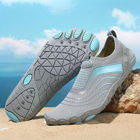 Gray and light blue water hiking shoes on a beach with a clear sky.