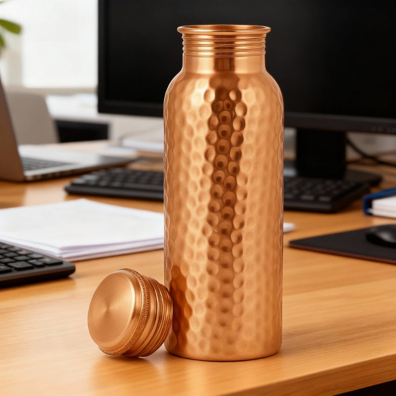 Copper water bottle with textured design on a wooden desk