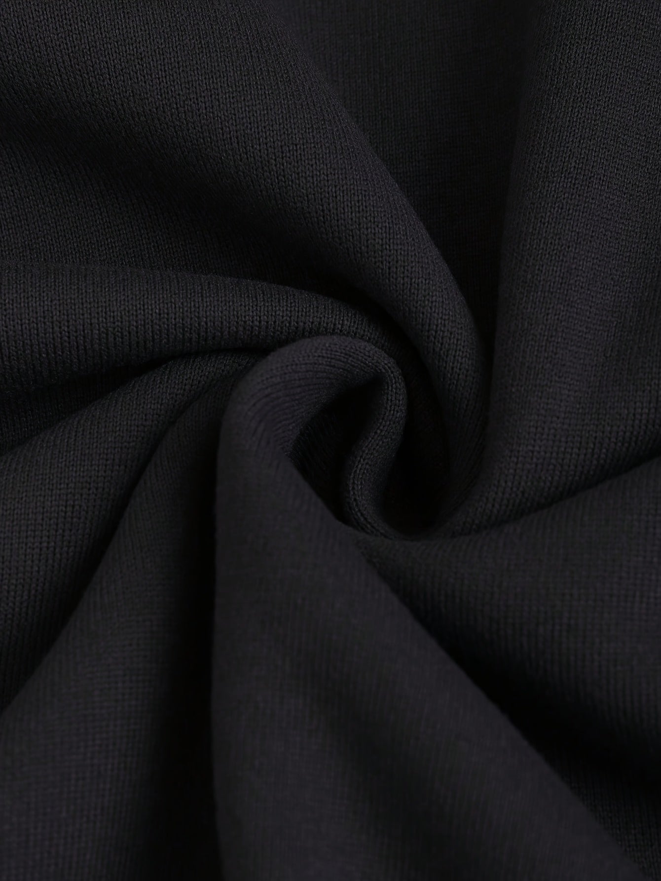 Close-up of black fabric with folds of a women’s hooded zip-up sweatshirt sold by 100 Spartans on a light gray background