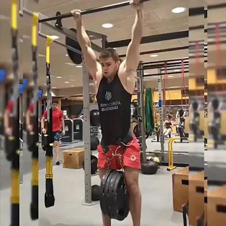 Person performing pull-ups in a gym setting while wearing a black weighted dip belt