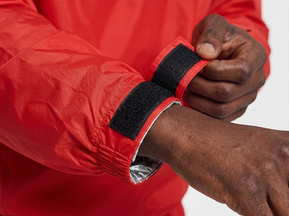 Person wearing a red sauna suit with a black wrist lock on a white background