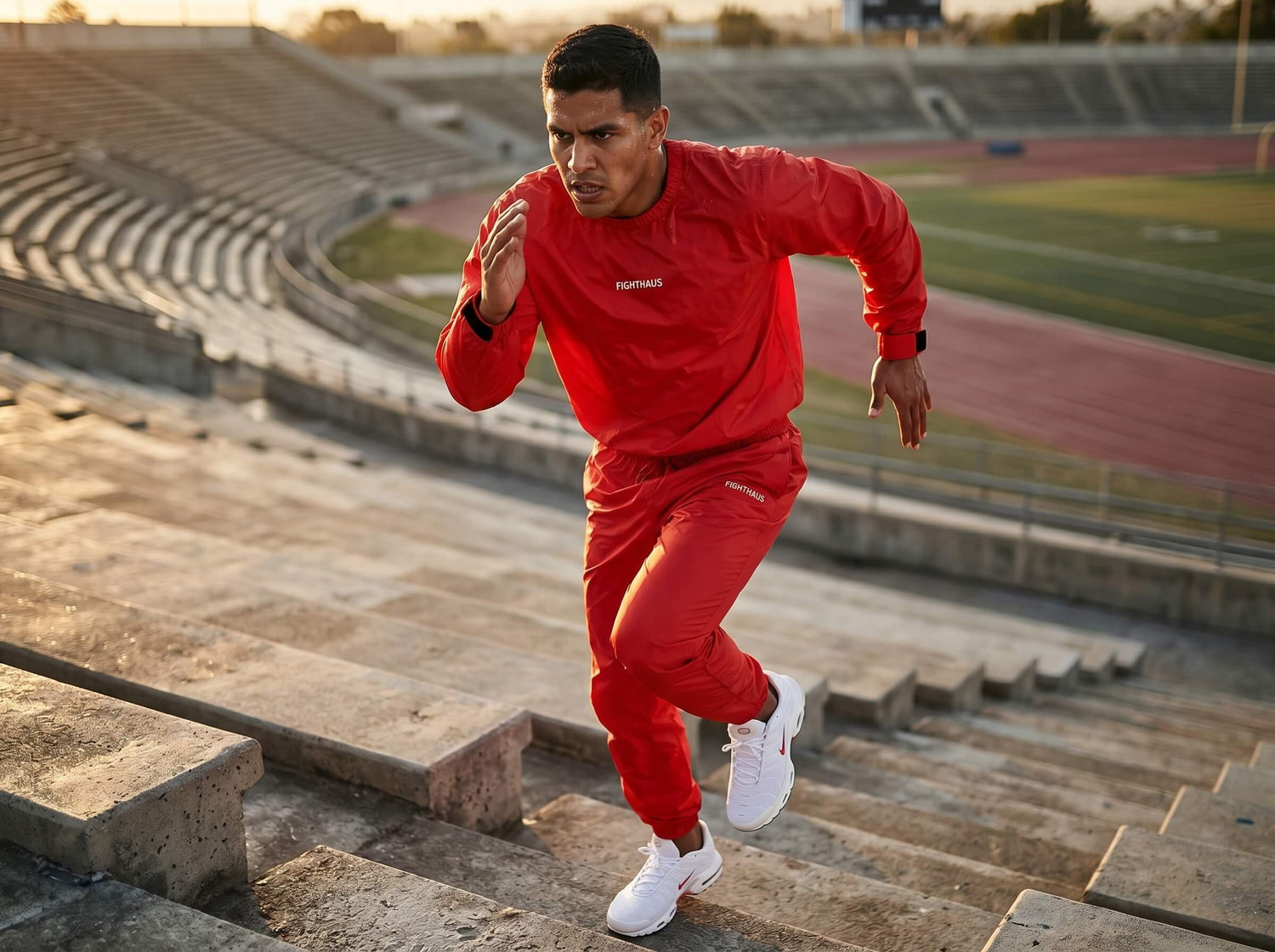Person in a red sauna suit running on steps in an outdoor stadium.