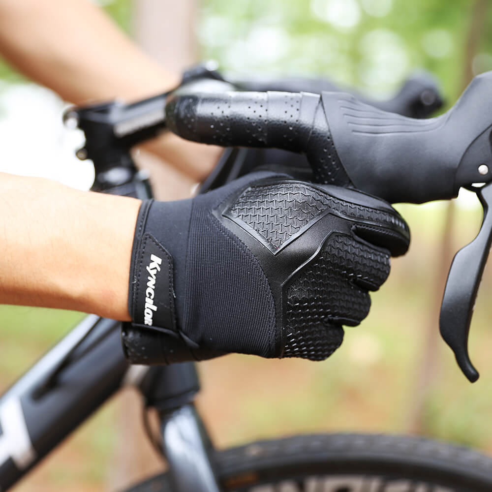Person wearing black  full finger workout gloves on a bicycle with a blurred natural background