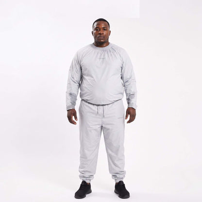 An overweight black man wearing a light grey sauna suit