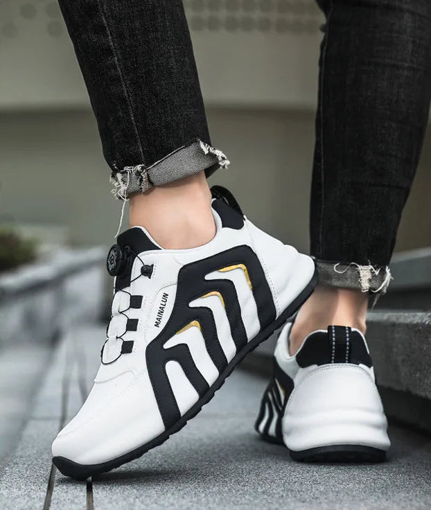 White and black sneakers with gold accents worn by a person on a blurred background