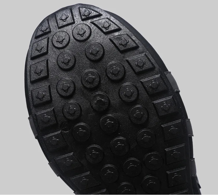 Close-up of a black rubber sole with tread pattern on a gray background