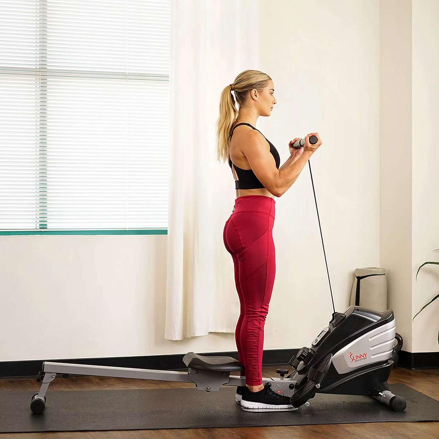A woman working out with a sunny magnetic rowing machine sold by 100 Spartans
