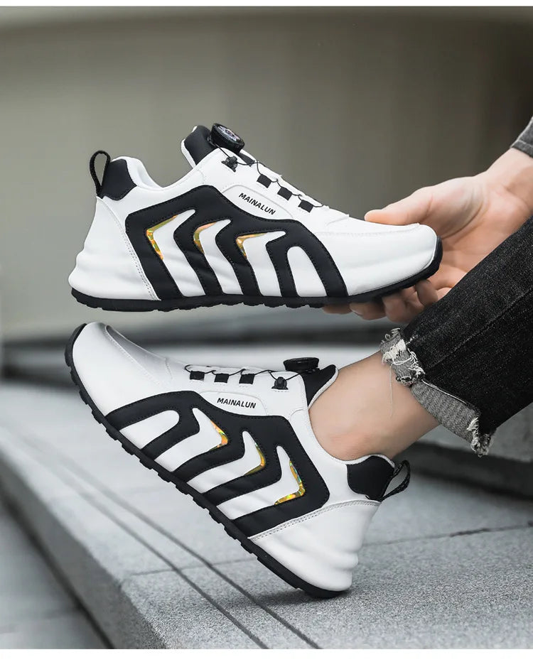 White sneakers with black and gold accents being worn on a gray pavement.