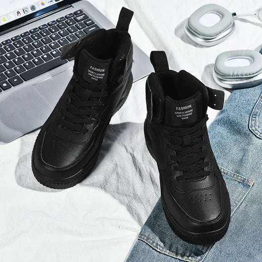 Black high-top sneakers on a white surface with a laptop and jeans in the background.