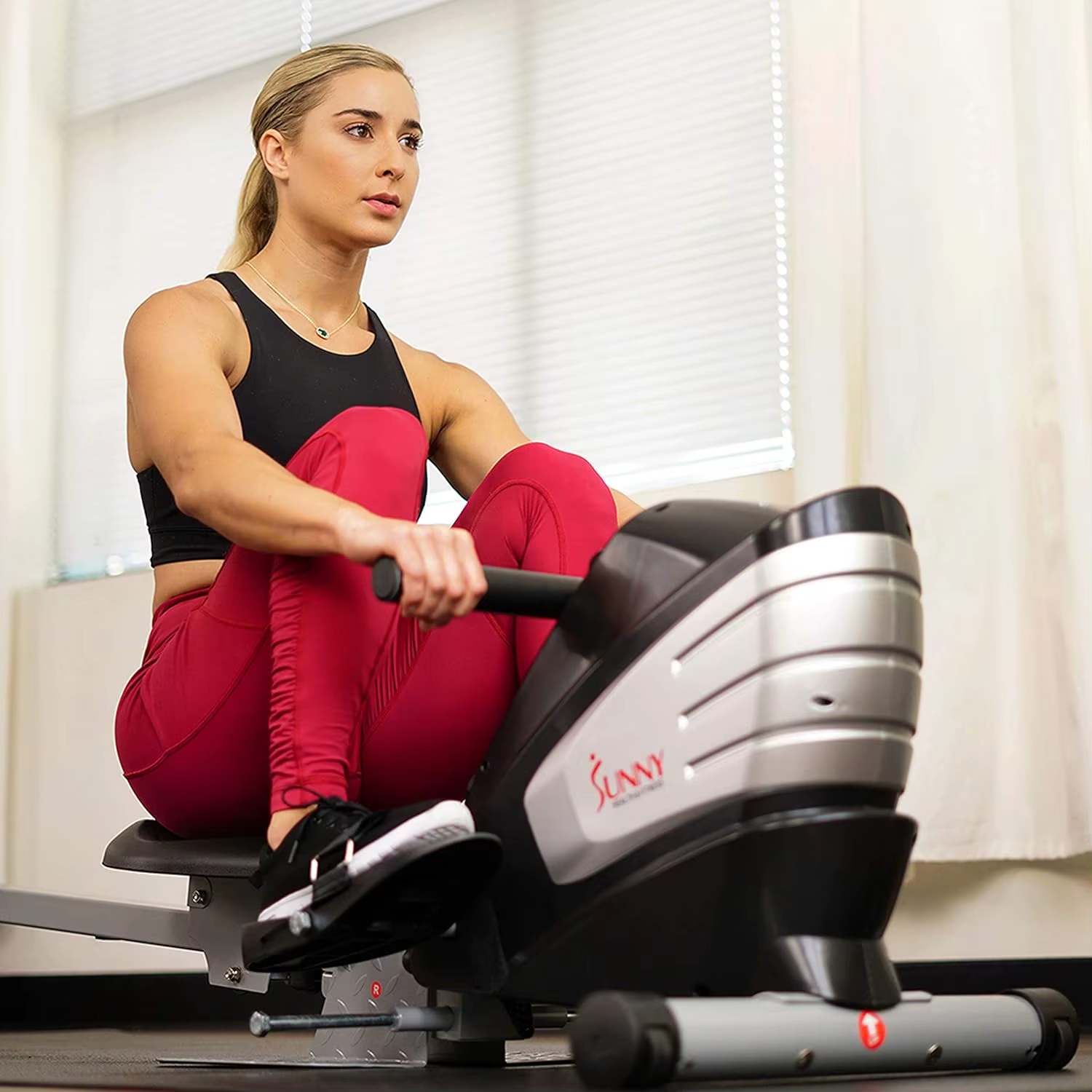 A woman working out with a sunny magnetic rowing machine sold by 100 Spartans