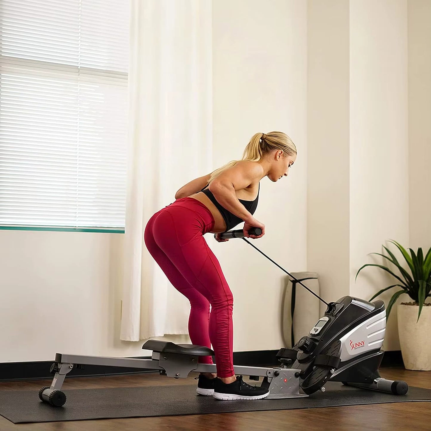 A woman working out with a sunny magnetic rowing machine sold by 100 Spartans