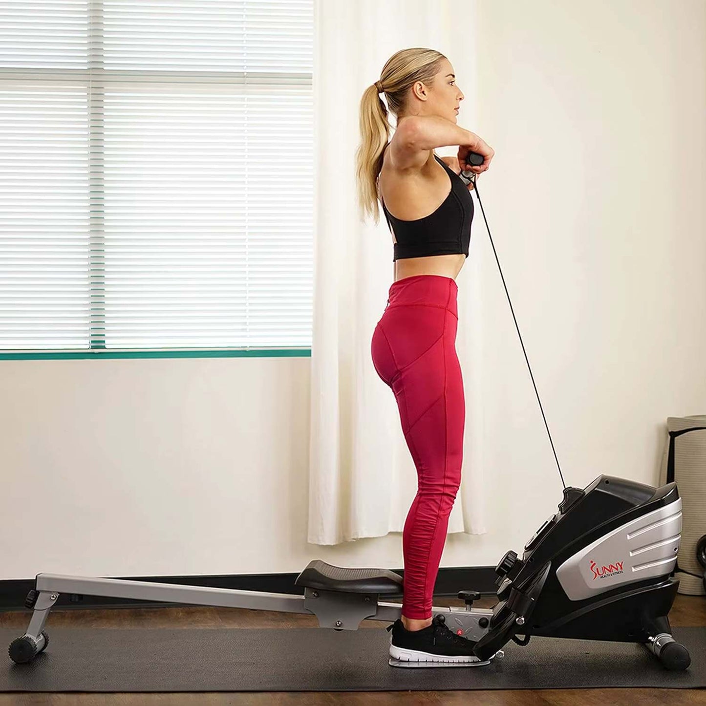 A woman working out with a sunny magnetic rowing machine sold by 100 Spartans