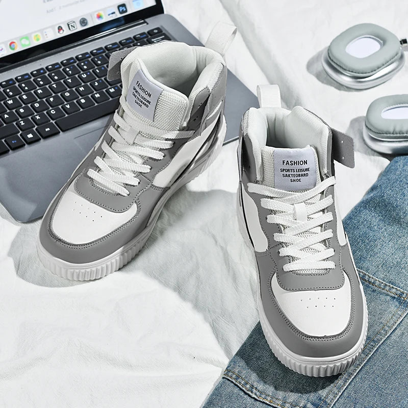 Gray and white sneakers on a surface with a laptop and other items in the background