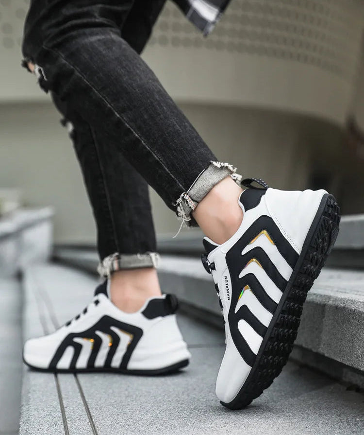 White sneakers with black and yellow accents worn by a person on a concrete surface.