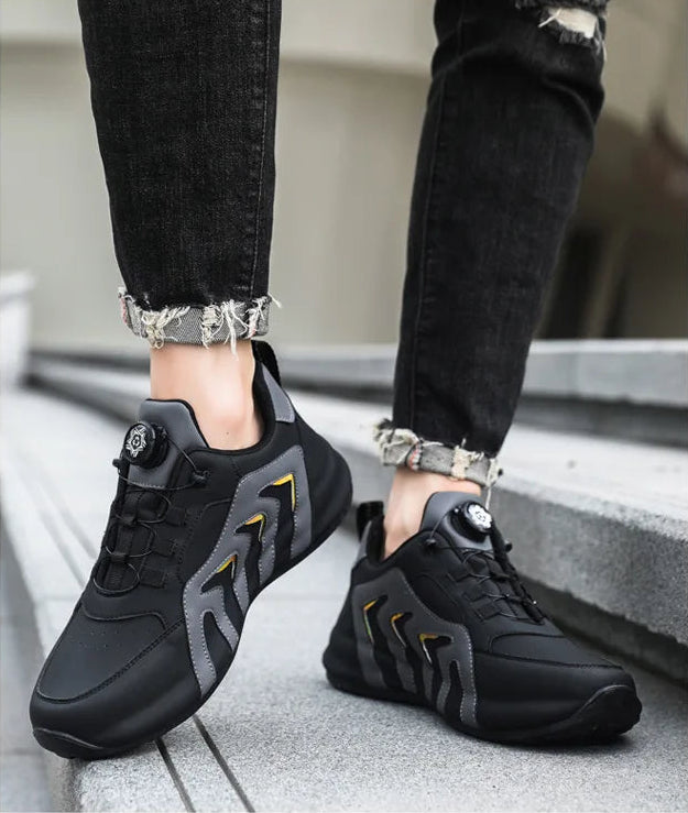 Black sneakers with gray accents worn by a person on a neutral background