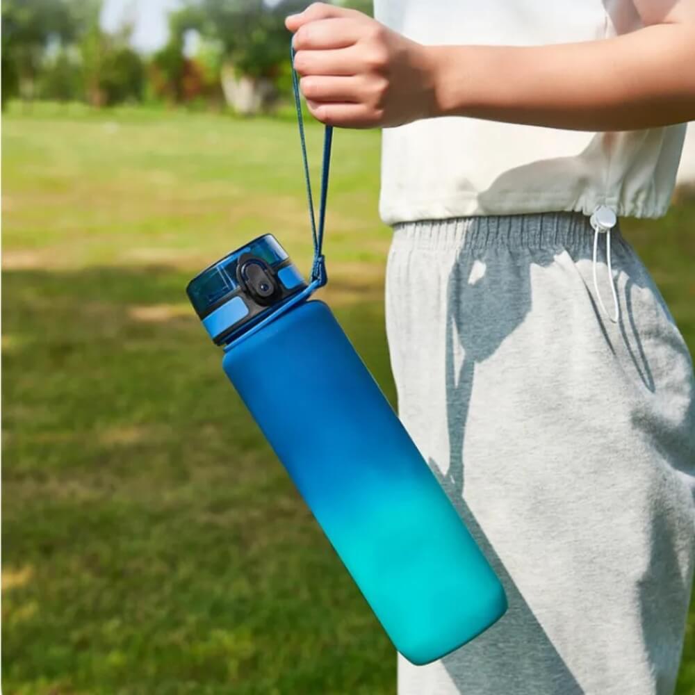 A man holding blue and green sport water bottle sold by 100 Spartans