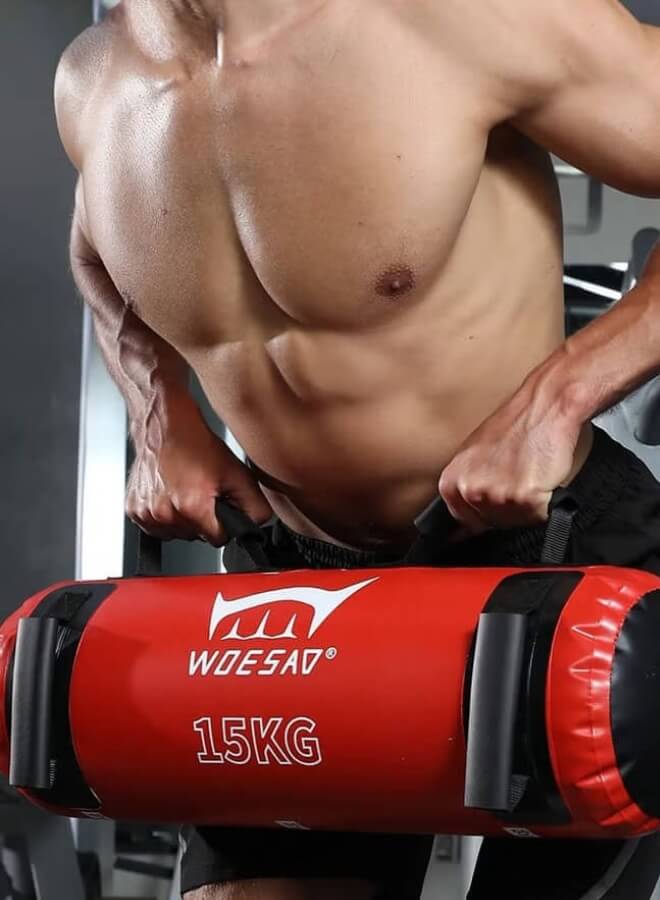 Person using a red and blackwater weight bag​ in a gym setting