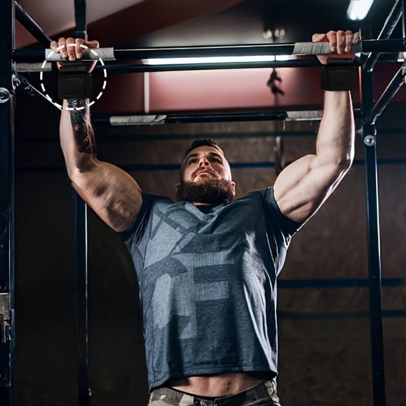 Man performing pull-ups in a gym setting with a weight lifting hooks