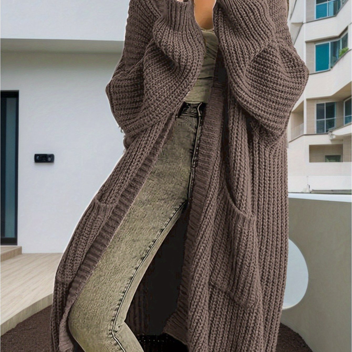 Person wearing a long brown knitted cardigan in an urban setting