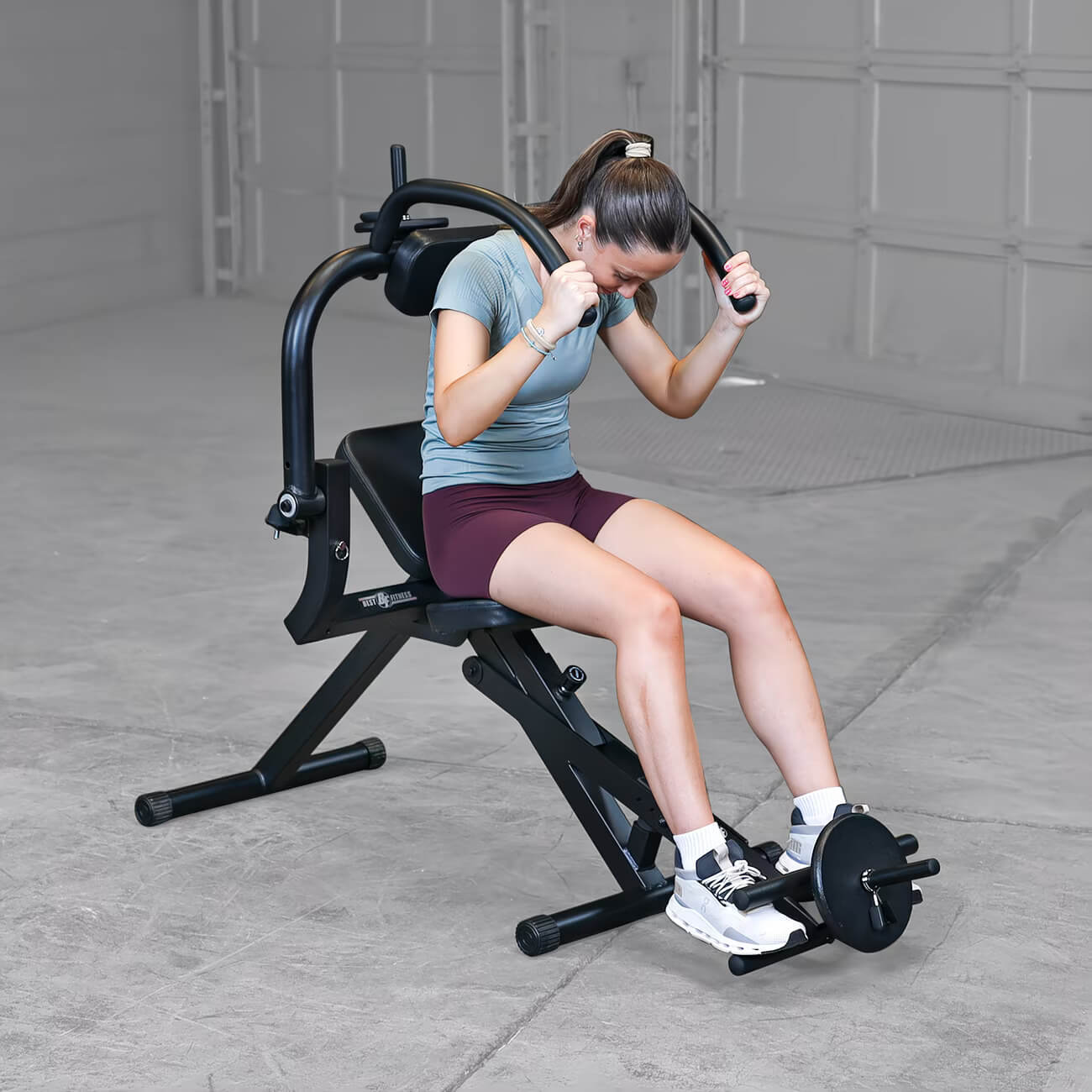 Woman exercising on a semi-recumbent ab bench in a garage setting