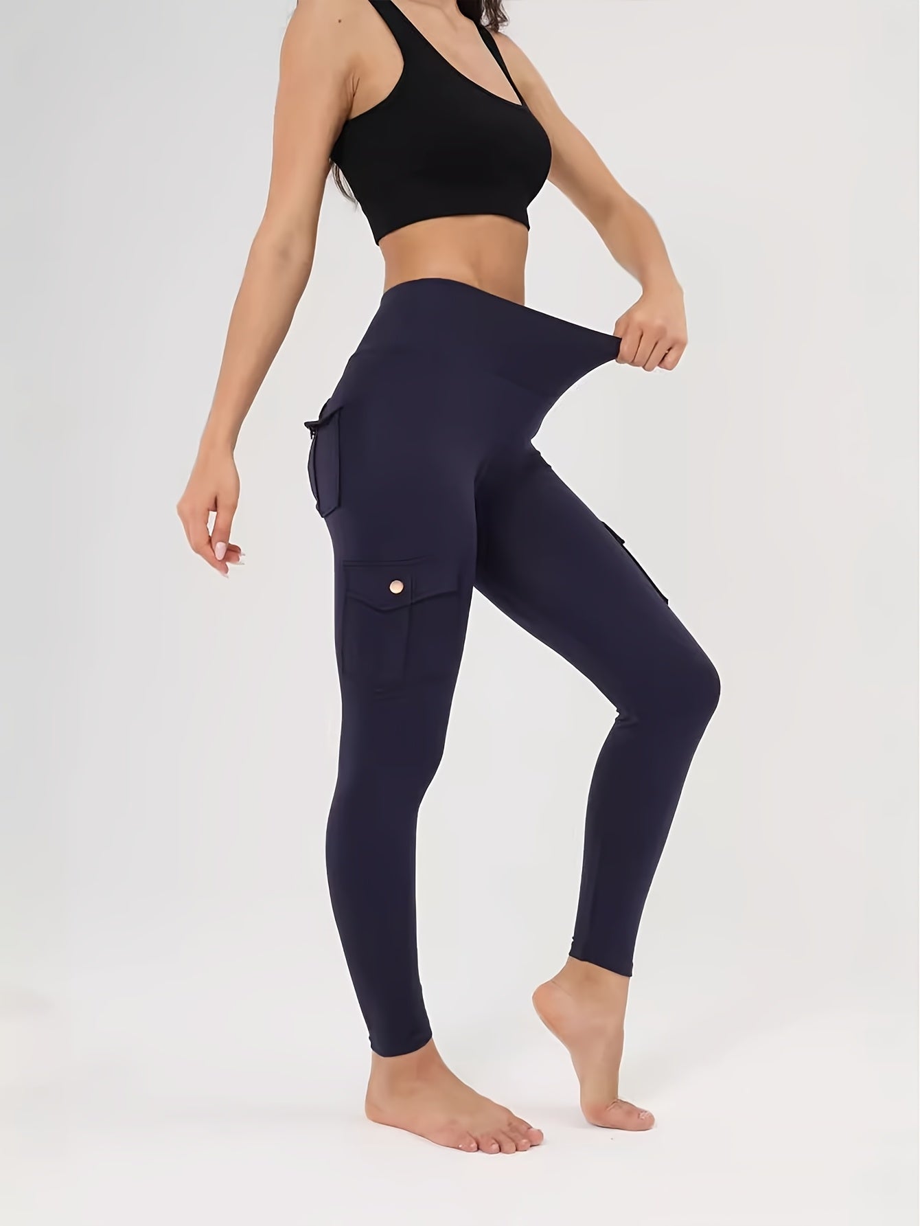 Person wearing navy cargo leggings and black sports bra on a white background