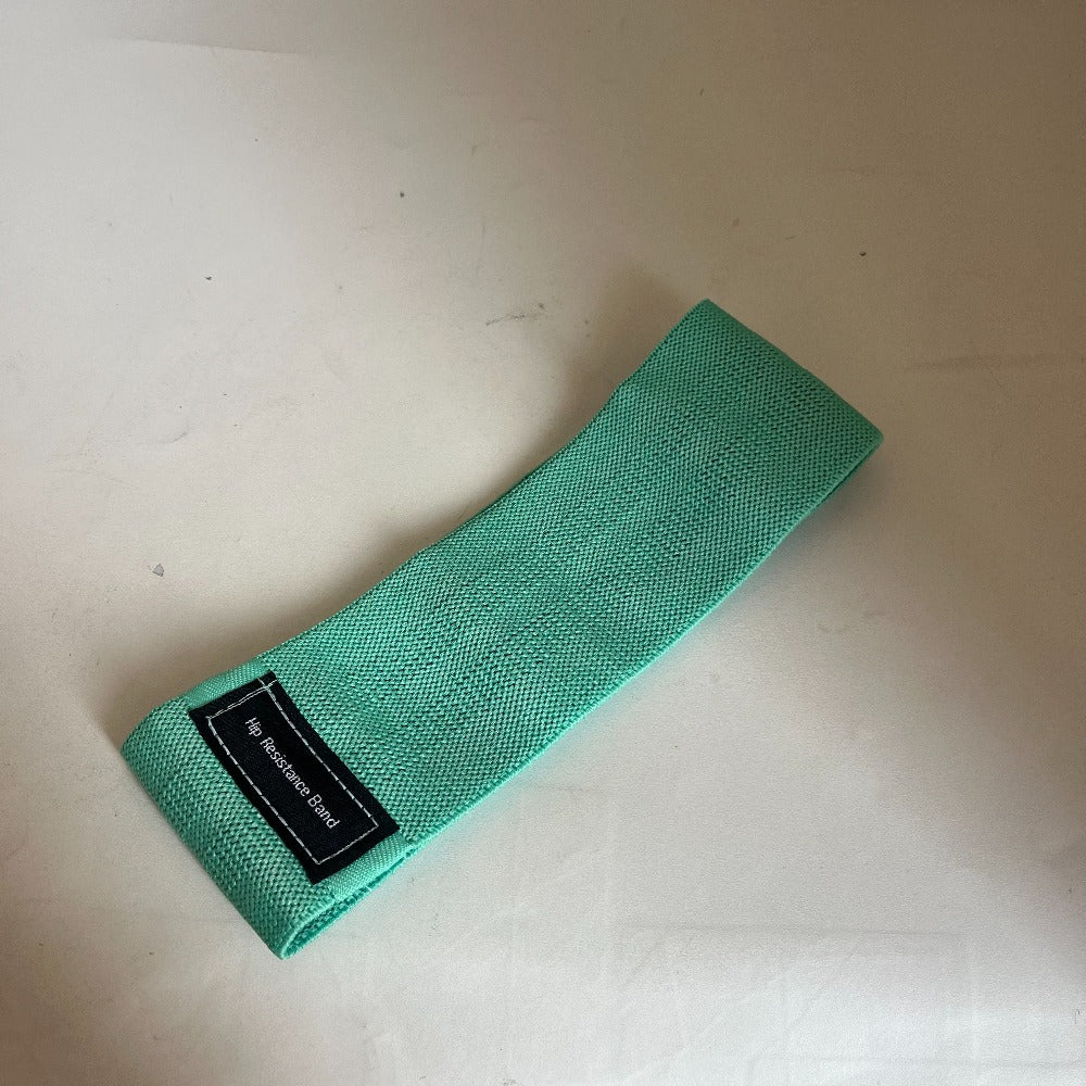 Green resistance band with a label on a light beige surface