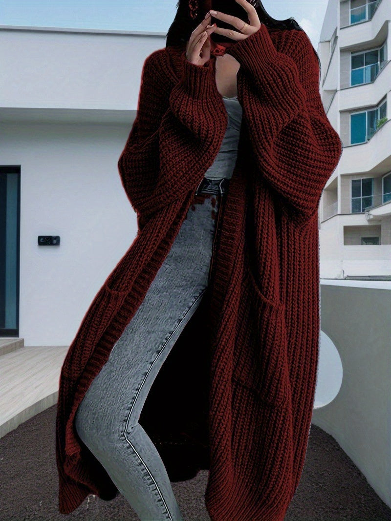 Person wearing a long burgundy knitted cardigan in an urban setting