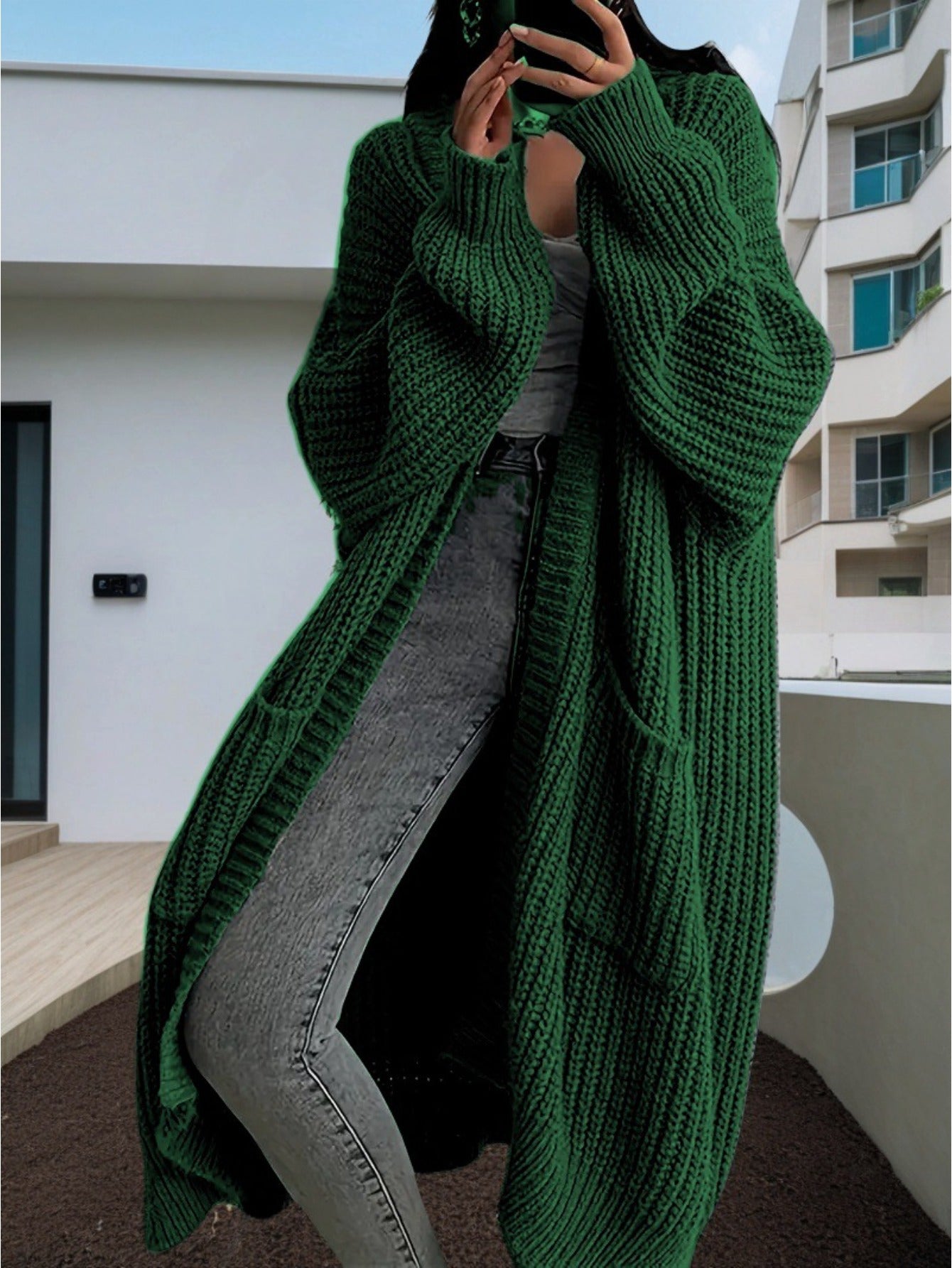 Person wearing a long green knitted cardigan in an urban setting