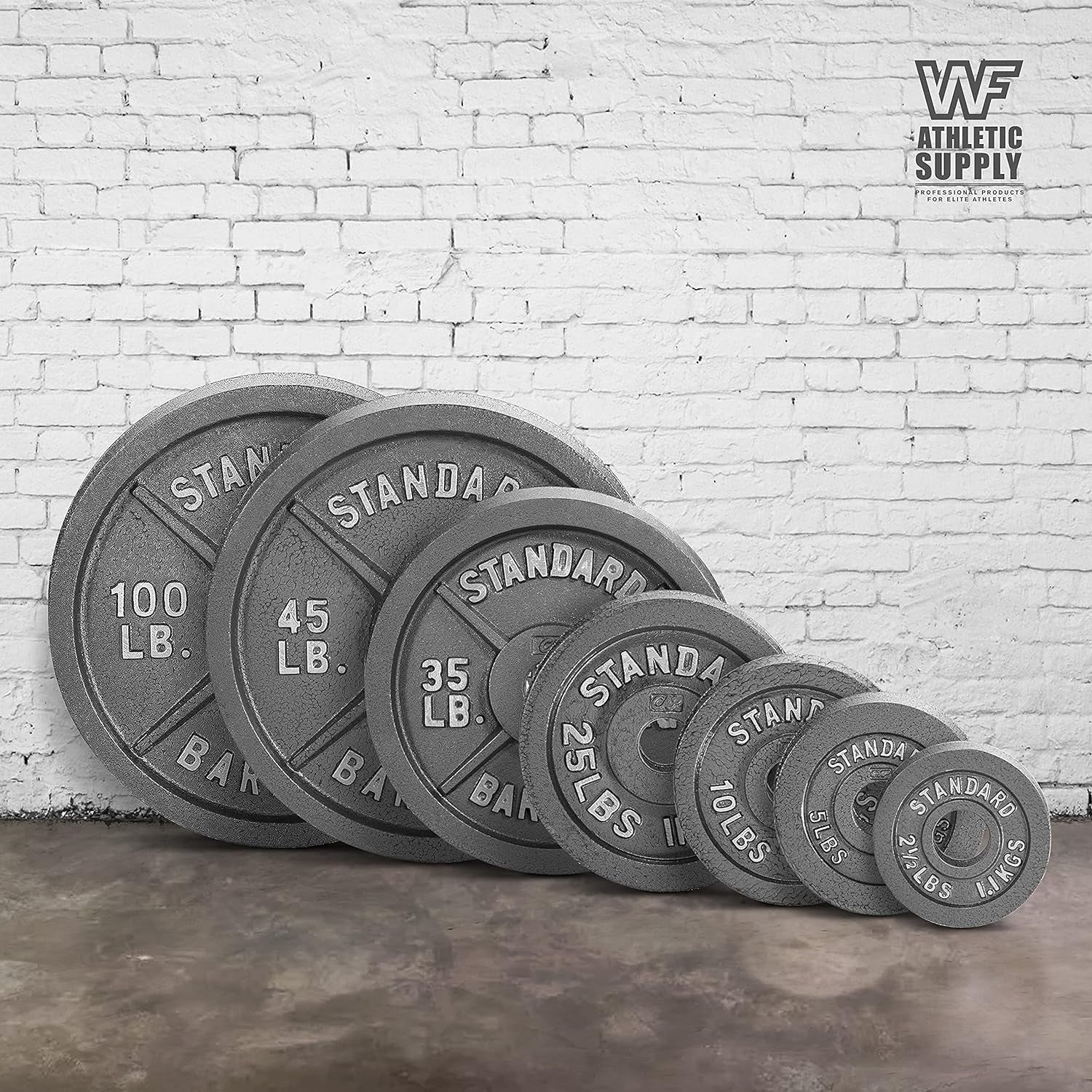 Set of weight plates against a white brick wall.