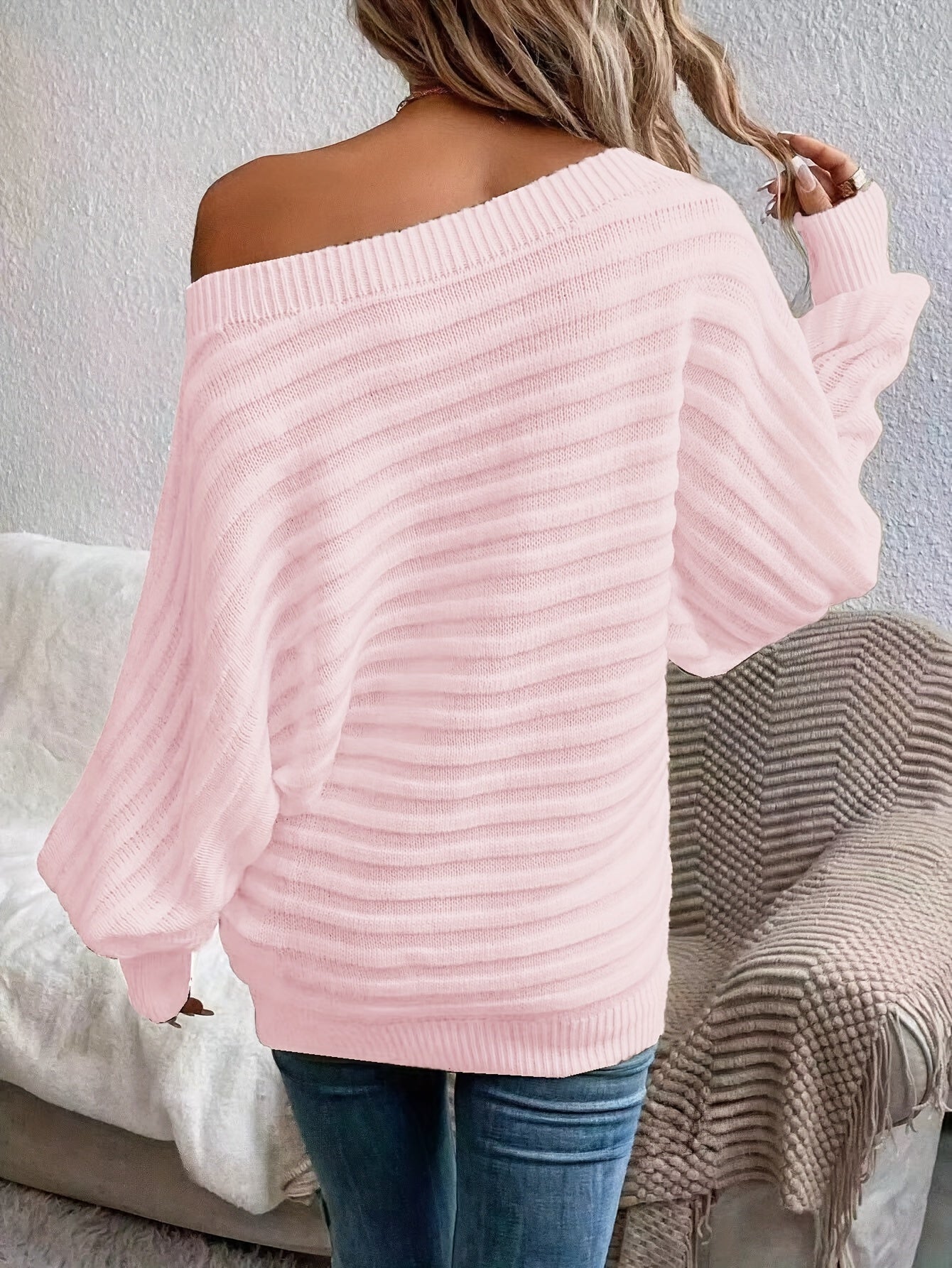 Person wearing a pink off shoulder sweater sitting on a couch.