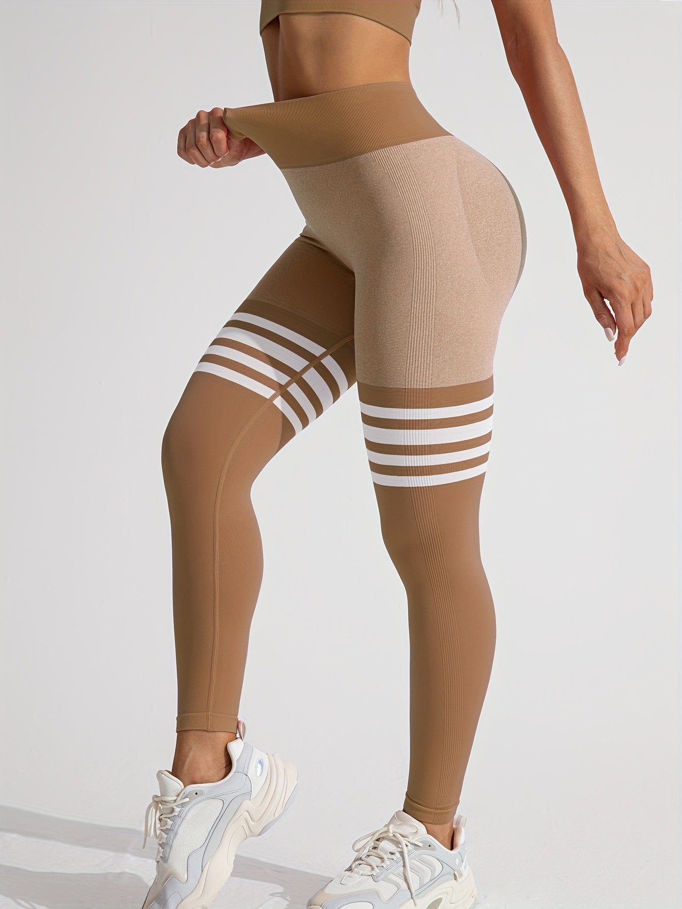 A woman wearing a brown yoga legging sold by 100 Spartans